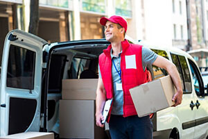 a courier in a red cap and vest carries a package