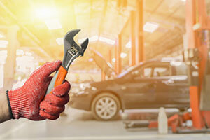 hand holding a wrench on the background of the car in the workshop