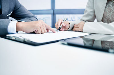the woman signs the document at the place indicated by the man